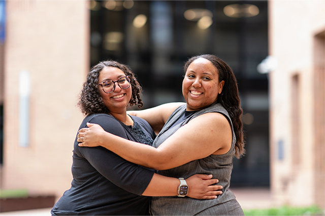 Gabrielle Black, left, and Alisha Atkinson embrace and smile during a portrait session on the UTRGV campus ahead of Spring 2026 commencement ceremonies.