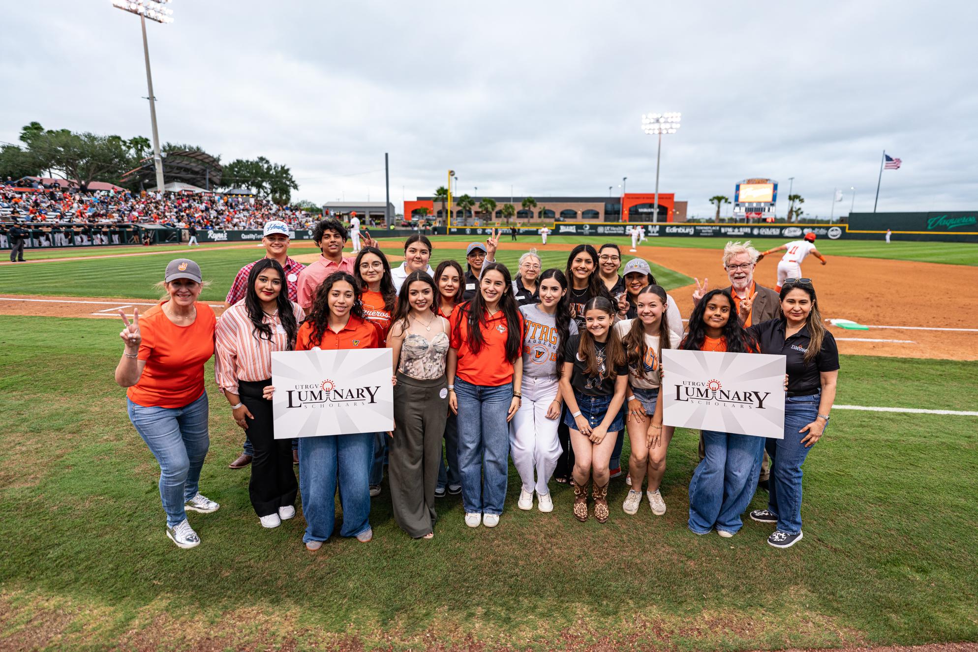 A group of people posing together on a baseball field
