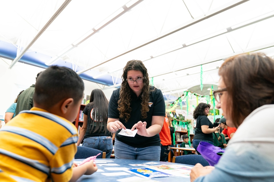Community outreach participant uses illustrated cards to explain insect research during an educational activity at a library.