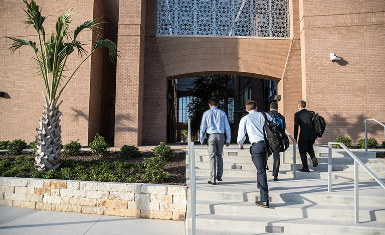 Four people carrying bags walk up a set of concrete ...