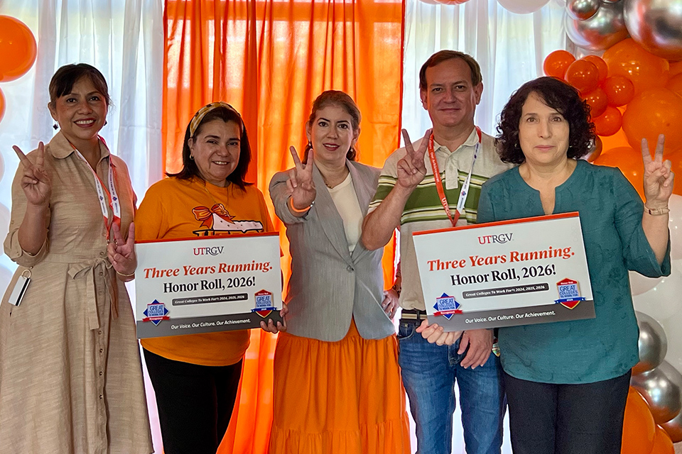 Five UTRGV employees celebrate in front of orange and white balloons while holding signs recognizing three consecutive years as a Great Colleges to Work For and the university’s 2026 Honor Roll distinction.
