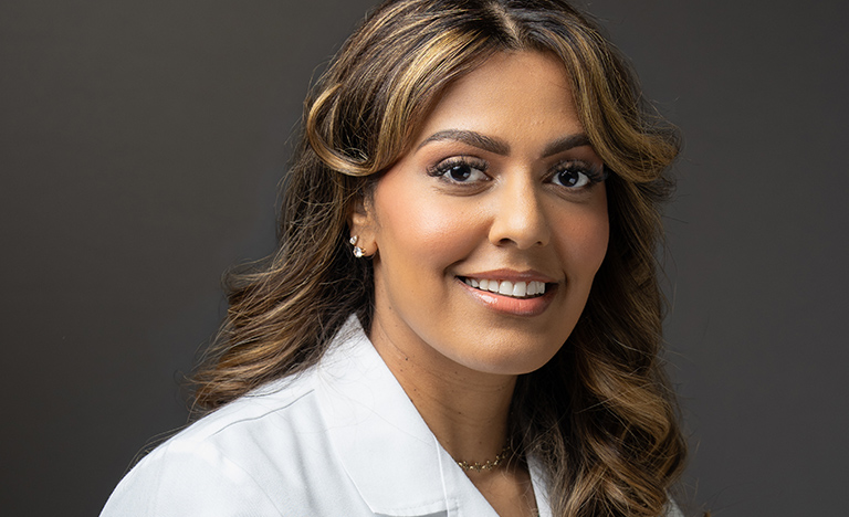 Portrait of Dr. Christine Elizabeth Loftis smiling in a white UT Health RGV medical coat against a dark background.