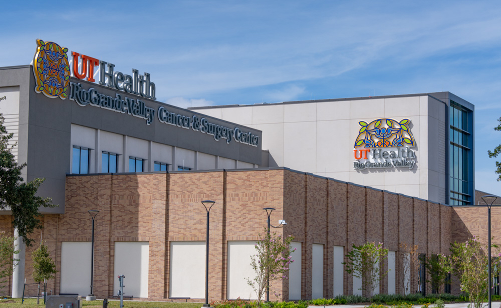 Exterior of the UT Health RGV Cancer and Surgery Center in McAllen, with university signage on its brick and gray facade.