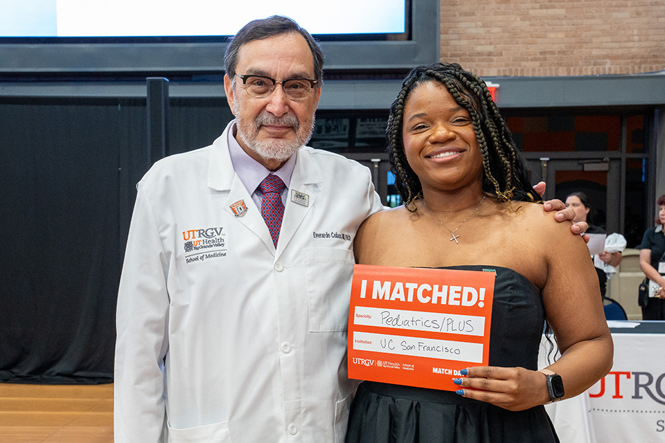 A smiling woman holds a "I Matched!" sign for Pediatrics at UC San Francisco, standing beside a man in a lab coat at a medical school event.