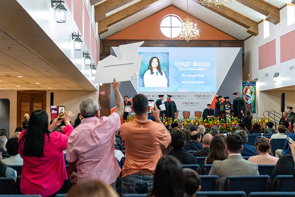 A family stands up to cheer for their graduate.