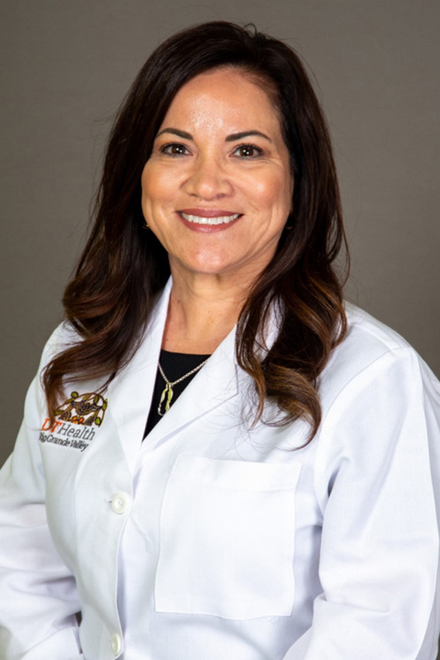 Smiling woman with long brown hair wearing a white medical coat, featuring a UTRGV logo, against a plain gray background. Professional and approachable tone.