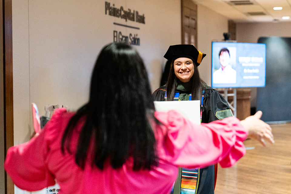 Graduate stops to hug a family member after receiving her diploma.