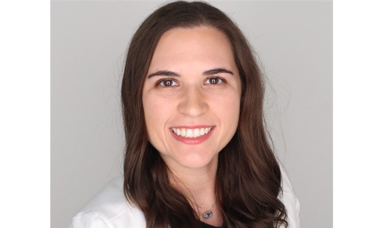 Heather Davis-Lopez smiles for a headshot in a white medical coat against a light gray background.