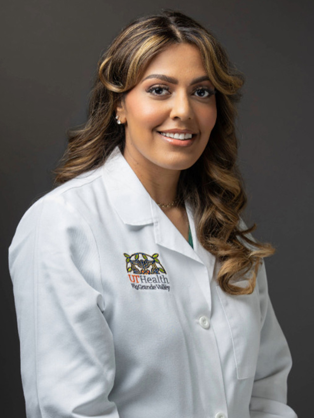 Portrait of Dr. Christine Elizabeth Loftis smiling in a white UT Health RGV medical coat against a dark background.
