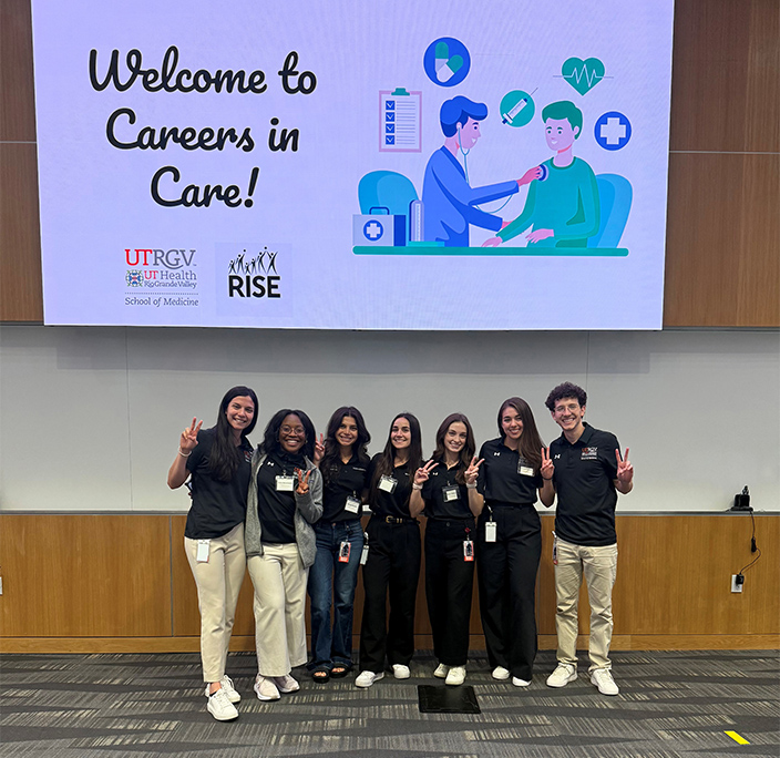 Seven UTRGV School of Medicine students, members of the RISE board, pose beneath a presentation slide promoting careers in health care. (UTRGV Photo)