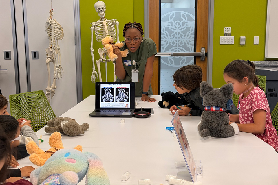 A UTRGV School of Medicine student teaches children about X-rays using a teddy bear during a RISE educational activity.