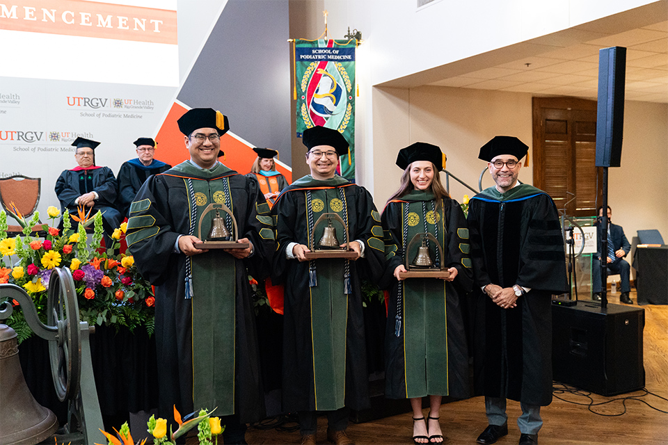 A group of graduates and the dean of the school pose for a photo.