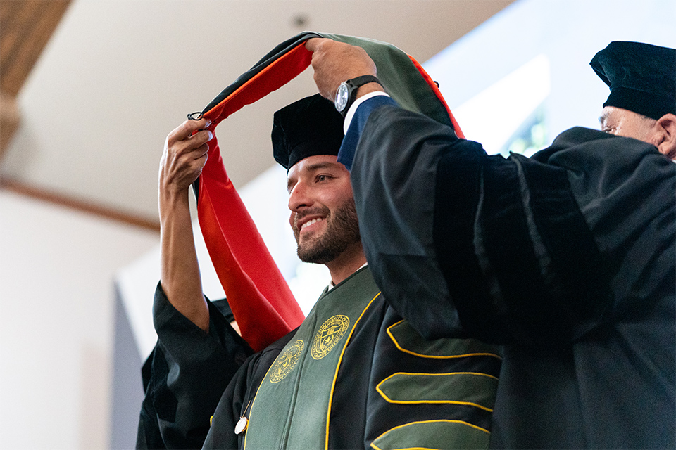 Graduate receives his hood during the ceemony.