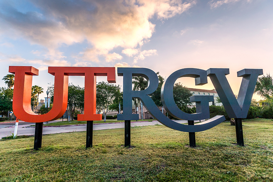 Giant letters spelling out U-T-R-G-V in front of a building with a cloudy day in the background.