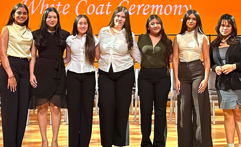 Seven people stand side by side on a stage during a ...
