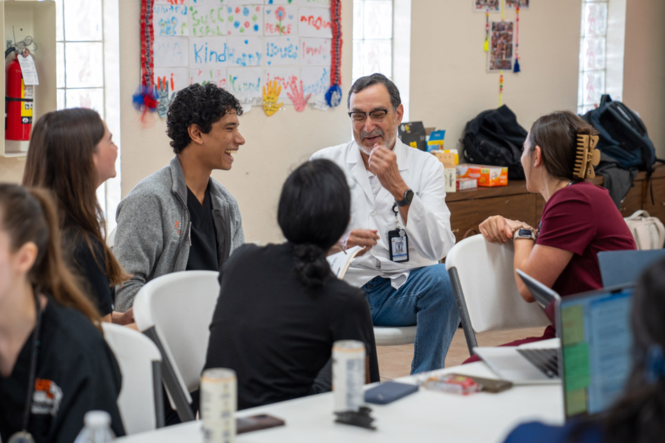UTRGV School of Medicine faculty and students gather around a table during a discussion, with Dean Everardo Cobos, MD, FACP, seated in the center and speaking with the group.