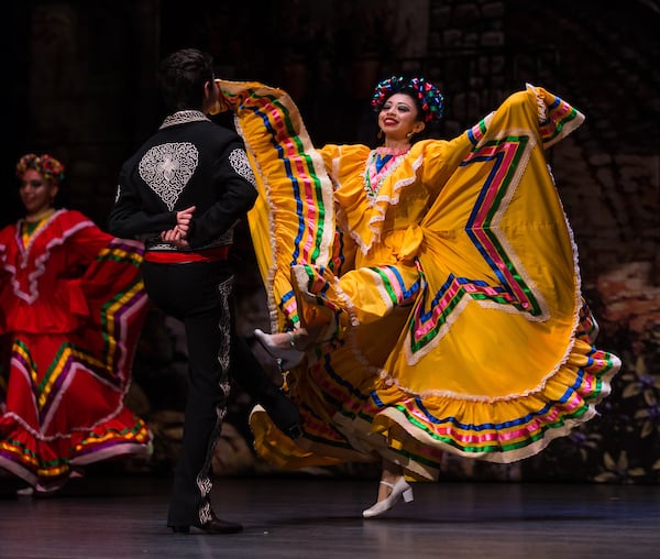 Folklórico dancers take the stage in bright colored dresses.