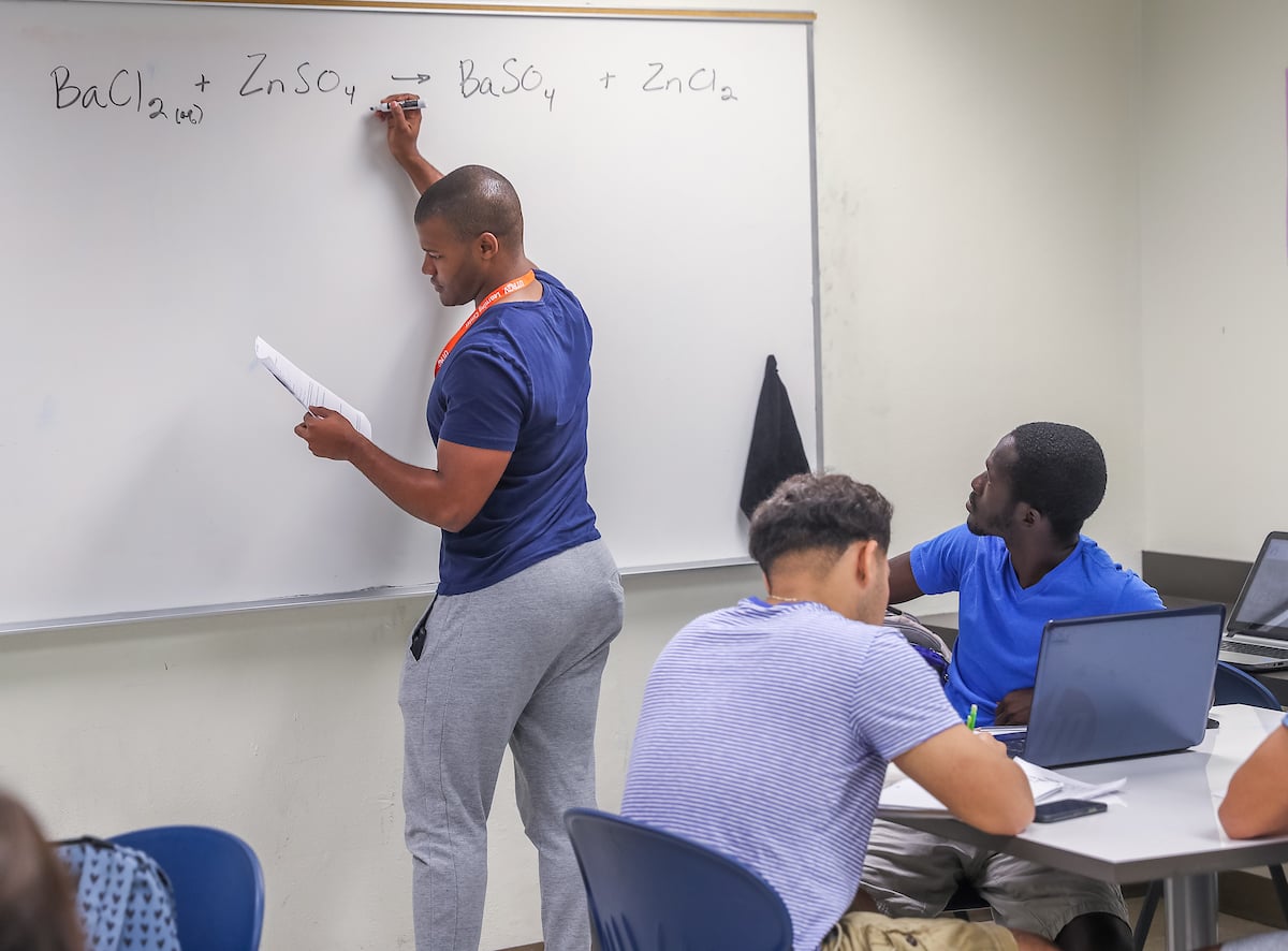 Tutor solves a mathematical problem on the white board.