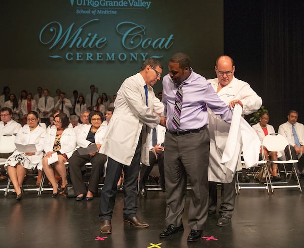 SOM Cohort 3 male student receives his white coat. 