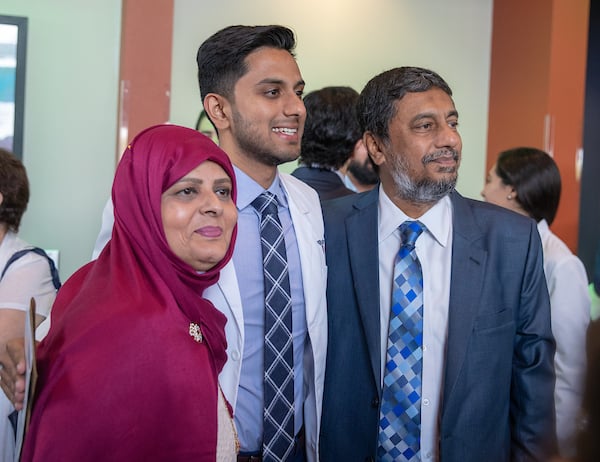 Student posing for picture with parents.