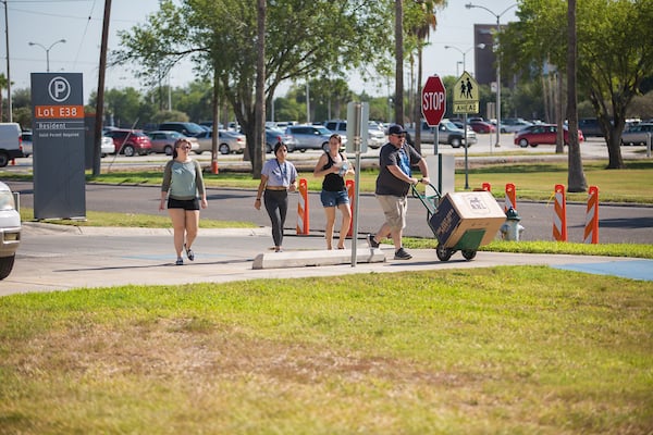 Gentleman helping freshman carry a large box on a dolly.