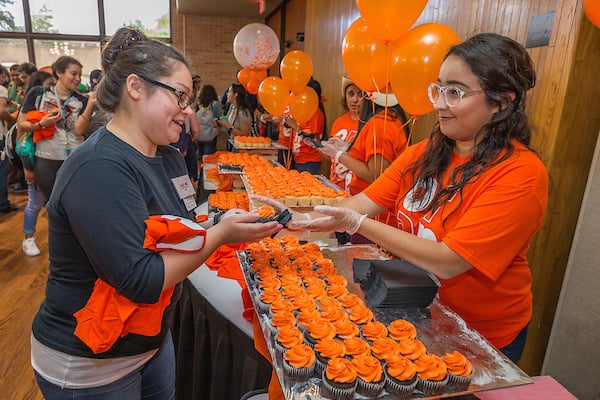 Thumbnail: Karla Castillo, Graphics Designer, handing out cupcakes to students.
