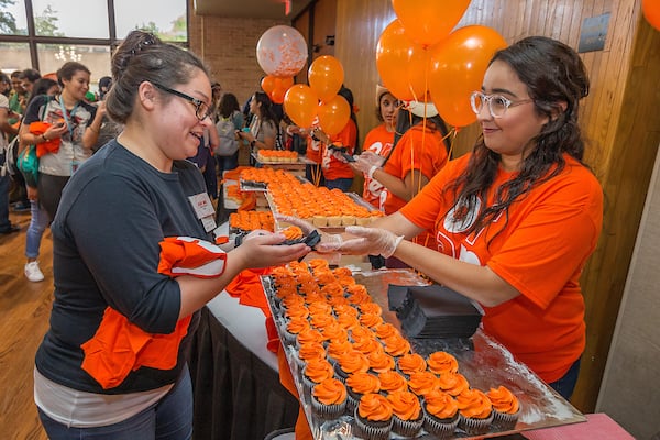 Karla Castillo, Graphics Designer, handing out cupcakes to students.