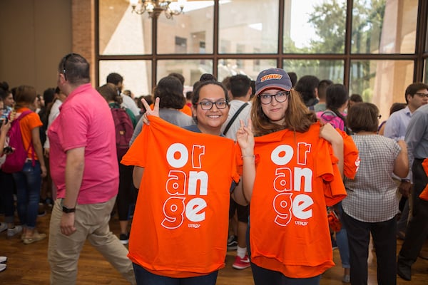 Two female staff holding Orange shirts showing V's up.