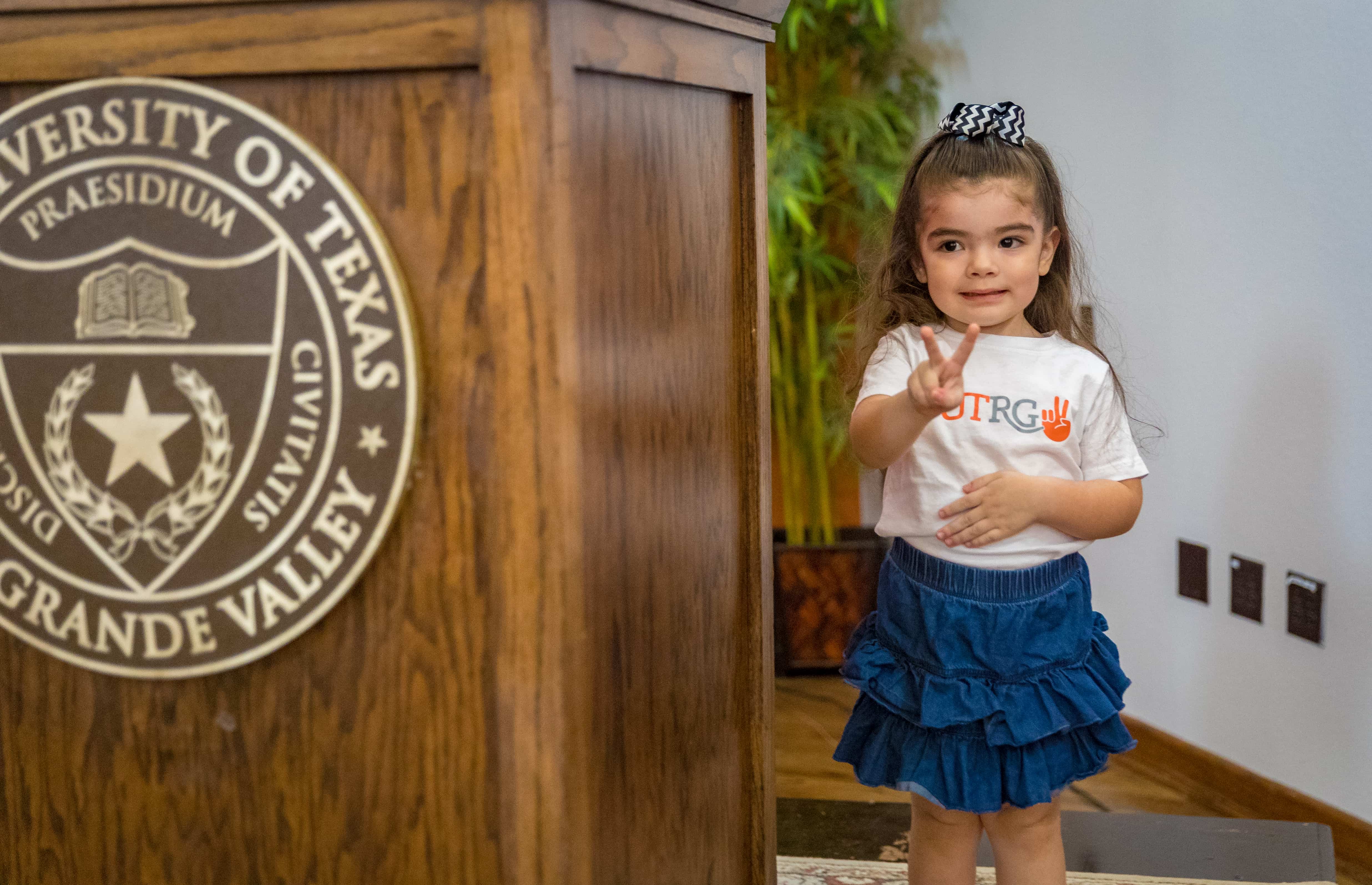 Baby Ava standing by podium showing her V's up.