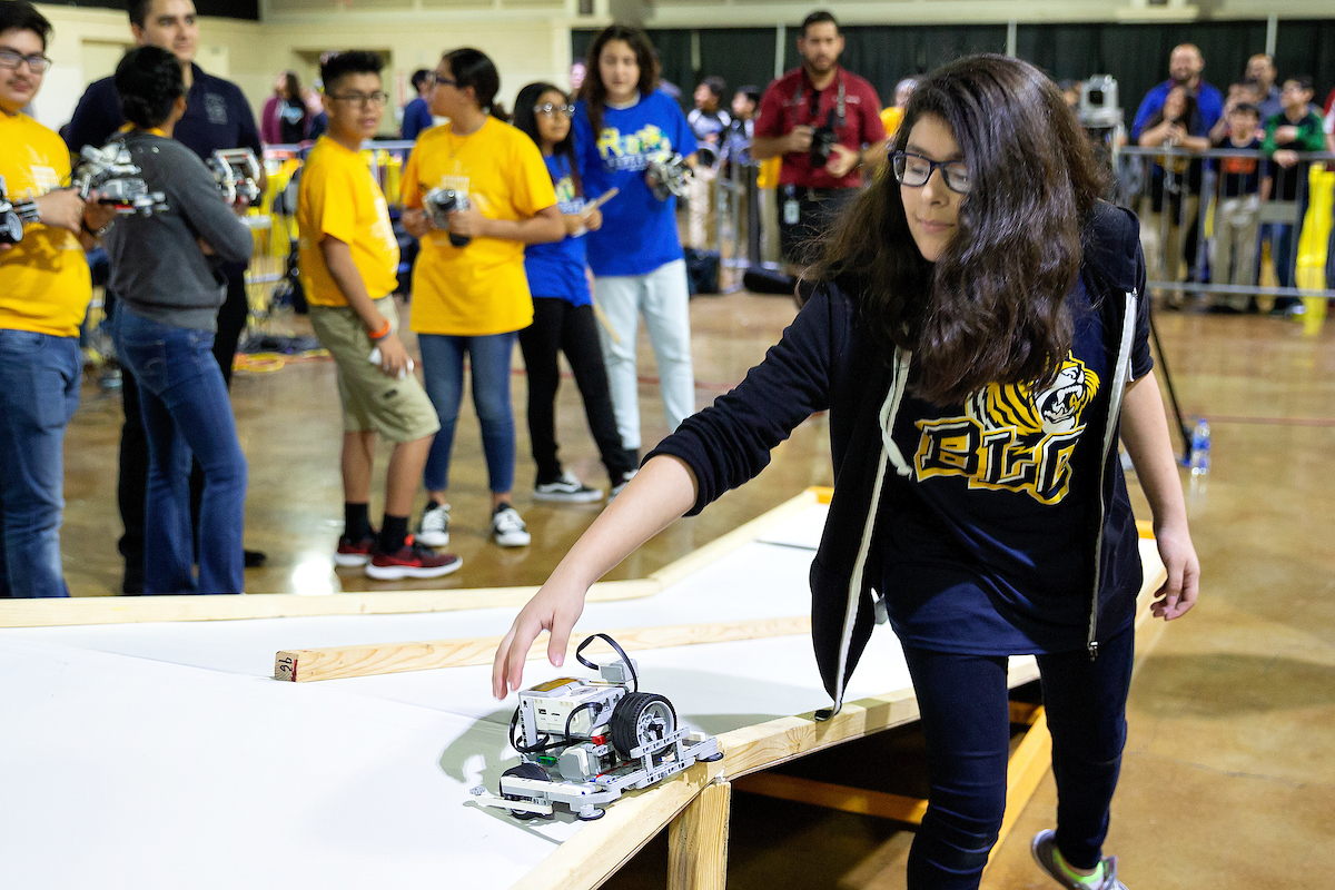 Student picks up robot from obstacle course.