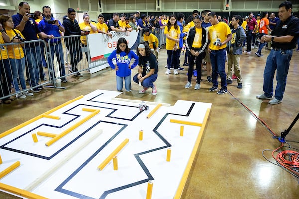 Teams watch as robot navigates course.