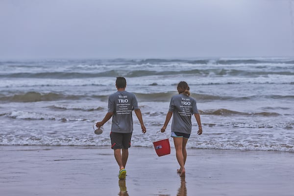 a pair of high school students carrying a buck to the beach for water to build sandcastles