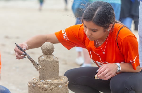 Talent Search high school student uses brush to finish sandcastle