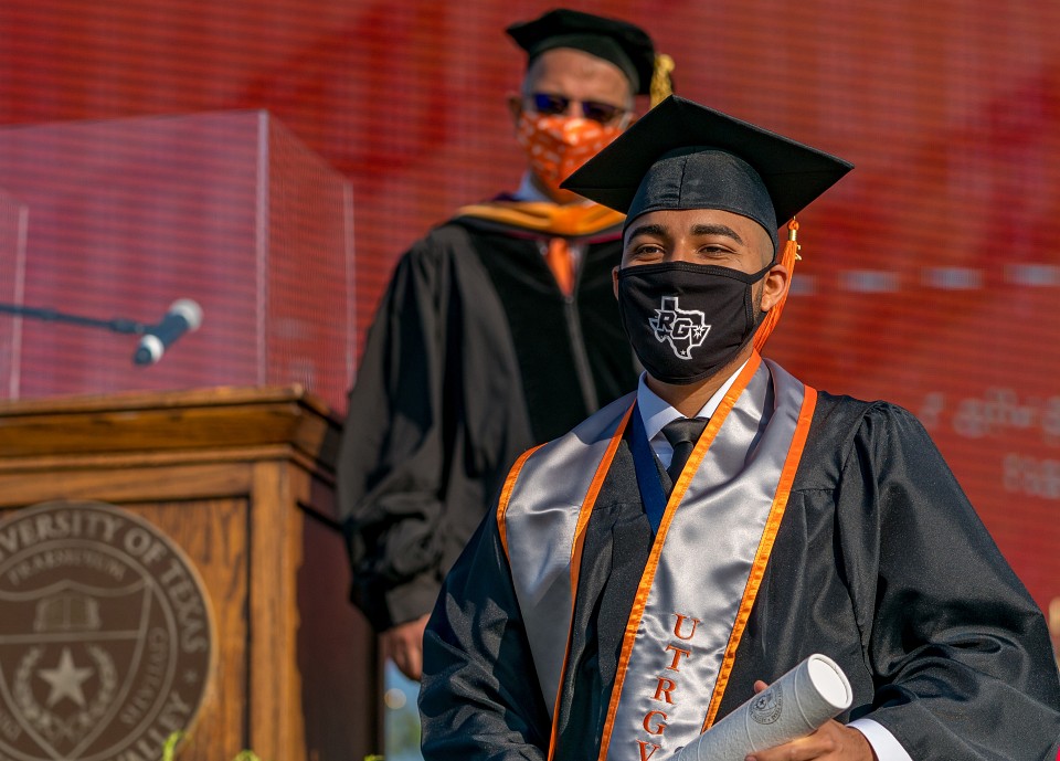 Dr. Ala Qubbaj standing behind graduate