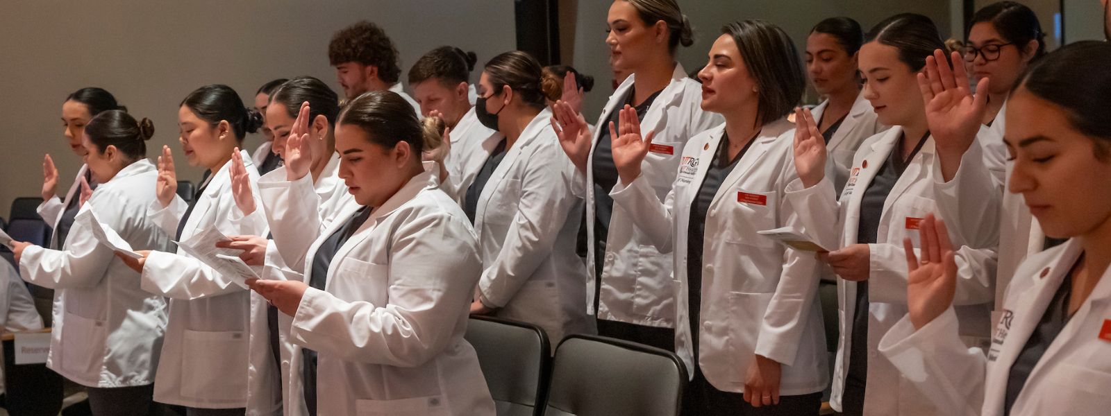 Nurses wearing coats during ceremony.