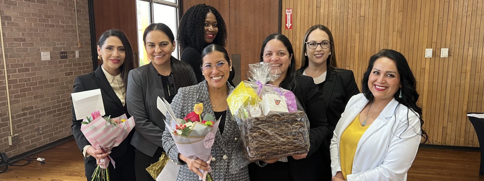 Students posing for camera while holding flowers and other gifts.