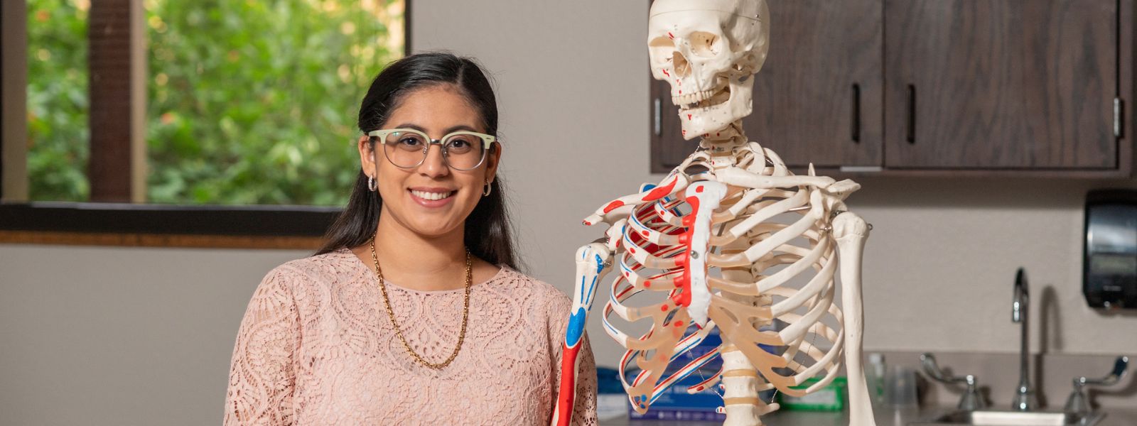 Student with skeleton smiling at camera.