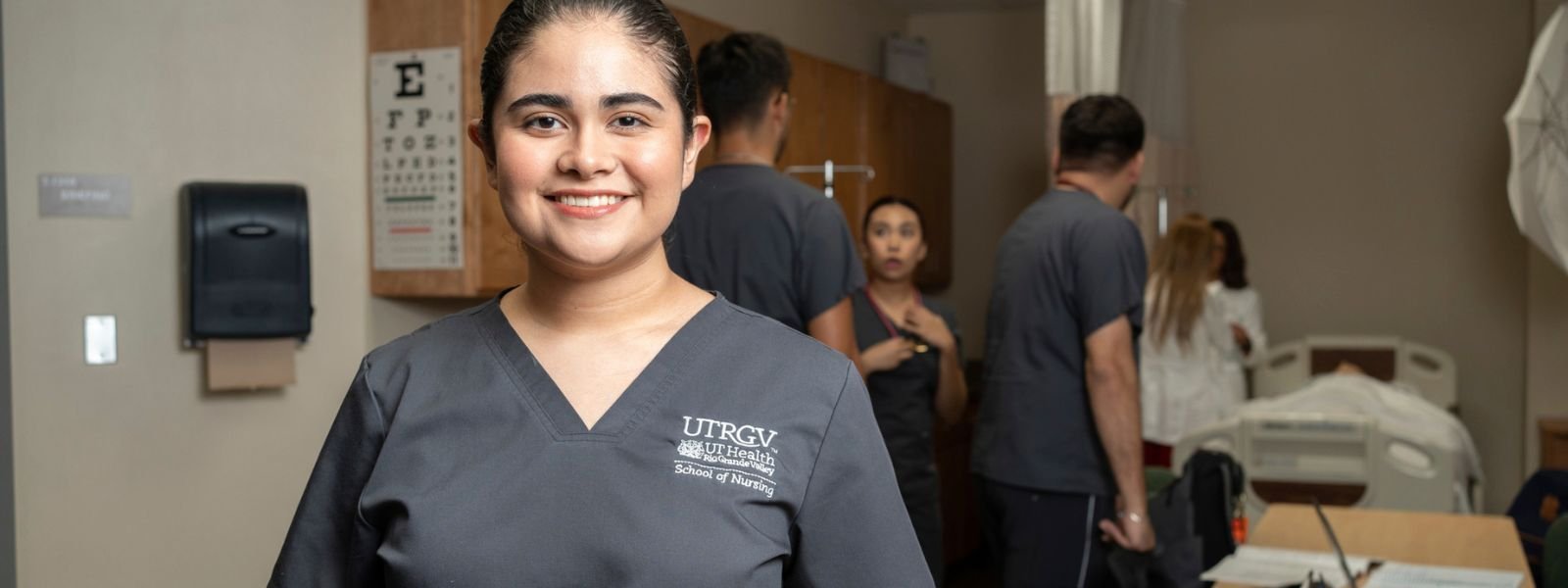 Student in gray scrubs in hospital setting.