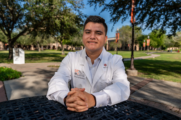 Student in white coat outdoors.