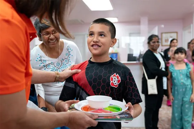 Student being handed a plate with food.