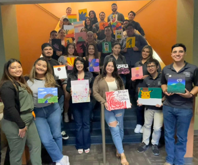Students posing for photo in front of staircase holding posters.