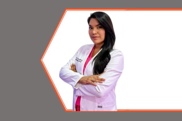 Student in white coat smiling at camera.