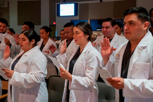 Group of nursing students raising their hands for a pledge