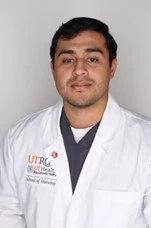 Student in white coat posing for photo while standing next to university's horse.