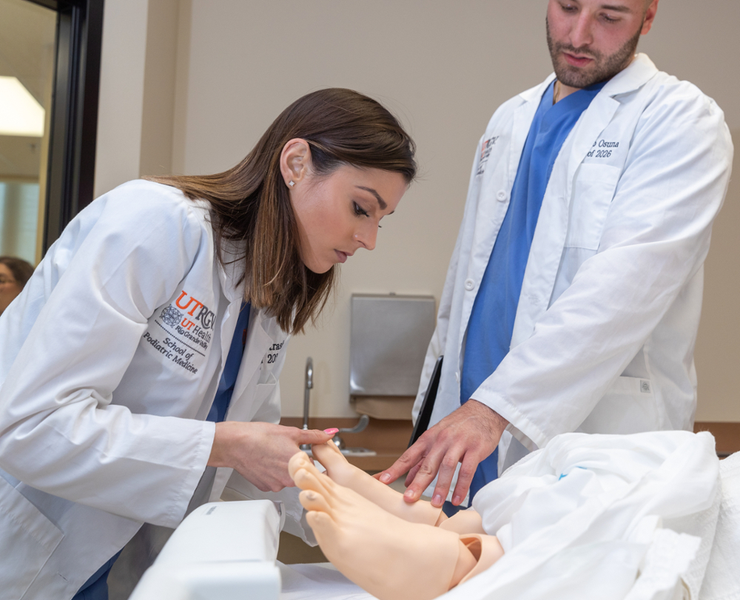 SOPM students in white coat assisting patient’s feet.