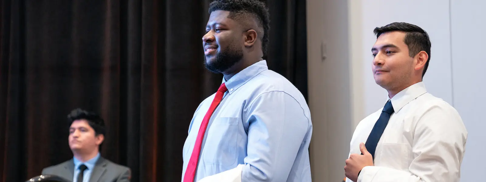 Students holding white coat onstage during white coat ceremony.