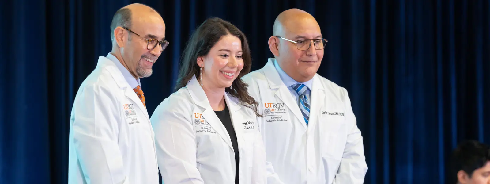Faculty, dean and student posing for photo during ceremony.