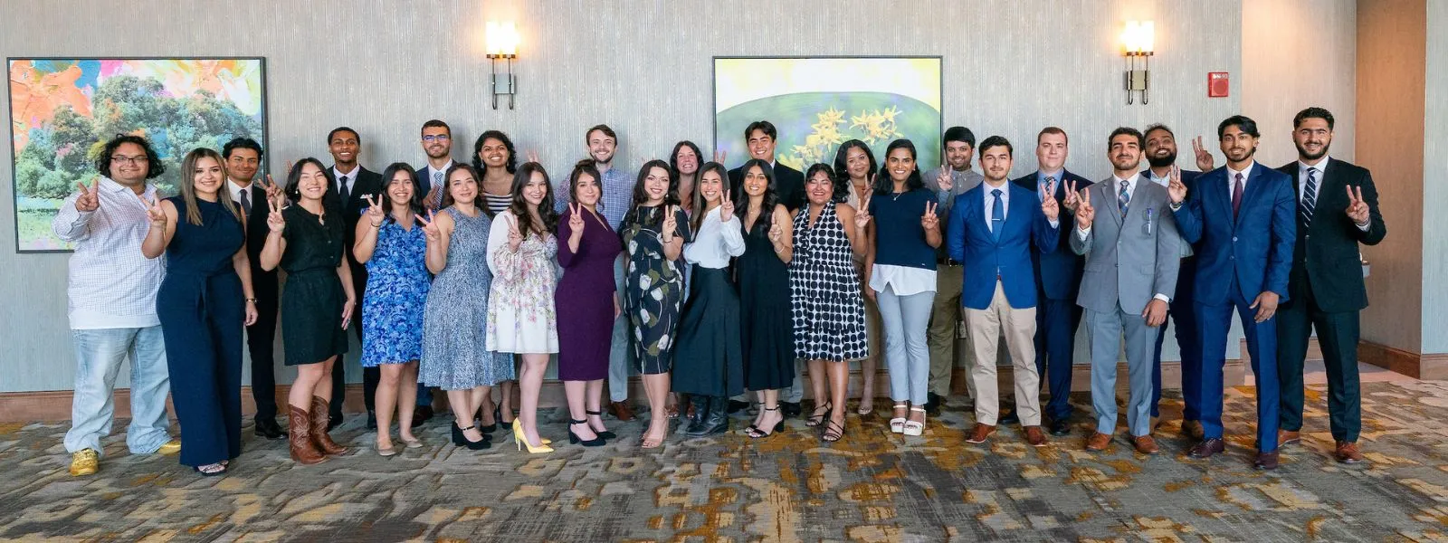 Group photo of students signaling v's up.