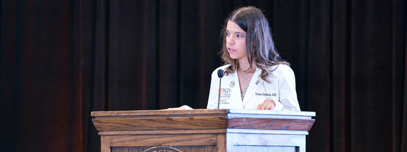 Faculty speaking onstage during event.