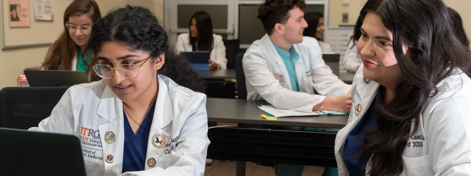 SOPM student working on computer with classmate next to her.